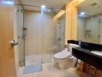 Bathroom with glass-enclosed shower, white toilet, vanity sink, and dark countertop in a 1-bedroom condo for sale at Park Point Residences, Cebu City.