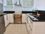 Modern U-shaped kitchen with white cabinets, black countertops, stainless steel range hood, and built-in stove in a Cebu City condominium.