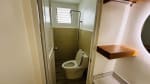 Compact bathroom with toilet, glass shower partition, and neutral wall tiles in a renovated bungalow for sale in Liloan, Cebu.