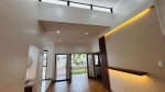 Modern living room with recessed ceiling lights, decorative illuminated wall panel, and sliding glass doors overlooking the outdoor area in Yati, Liloan.