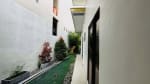 Narrow outdoor side passage with white walls, decorative plants, and tiled flooring at a modern tropical bungalow in Liloan, Cebu.