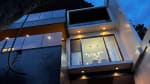 Modern three-storey house exterior at dusk featuring large glass windows, contemporary architecture, and illuminated interiors in Cebu City.