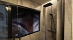 Modern bathroom shower area with dark wall tiles, glass partition, and a horizontal window with black blinds in a 3-storey Cebu City house.