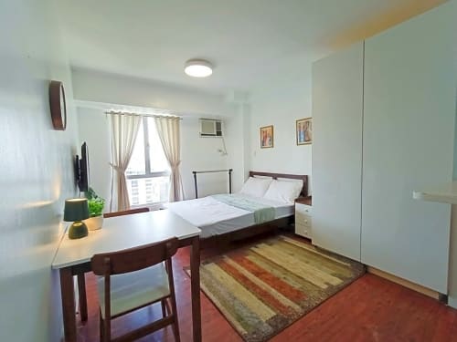 Furnished studio bedroom with double bed, dining table, wardrobe and window at Avida Towers 2 Cebu IT Park