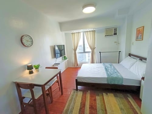 Furnished studio bedroom with bed, dining table, television and air conditioner at Avida Towers 2 Cebu IT Park