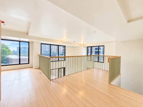 Spacious open loft interior with wood flooring and mezzanine railing in a 104 sqm condo for sale in Mandaue City