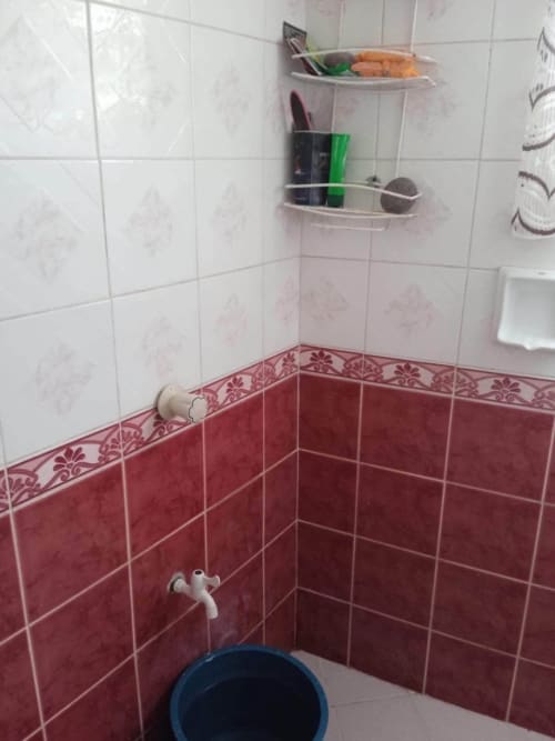 Bathroom with red and white tiled walls in a house and lot for sale in Buagson, Catarman, Cordova, Cebu.