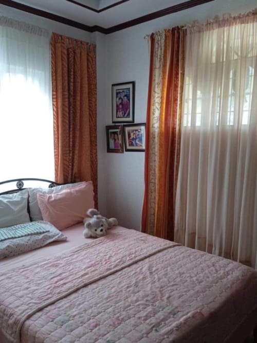 Bedroom with bed and window curtains in a 2-bedroom house for sale in Buagson, Cordova, Cebu.