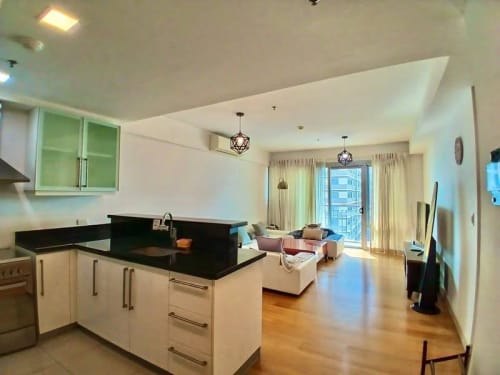 Open-plan kitchen and living area with black countertops, white cabinetry, dining space, and floor-to-ceiling windows at Park Point Residences, Cebu.