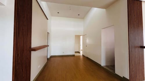 Empty interior hallway with white walls, brown wooden flooring, and doorways in a modern tropical bungalow for sale in Yati, Liloan, Cebu.