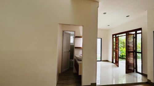Bright living area with white walls, glossy tiled flooring, and sliding glass doors opening to the porch of a modern bungalow in Yati, Cebu.