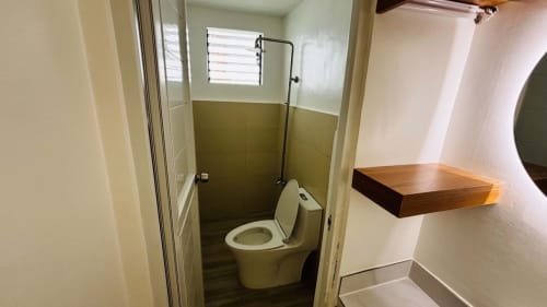 Compact bathroom with toilet, glass shower partition, and neutral wall tiles in a renovated bungalow for sale in Liloan, Cebu.
