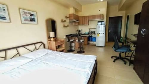 Bed, dining table, computer desk, and television in the open-plan interior of a fully furnished studio condo for sale at Avida Riala Tower 3, Cebu.