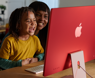 Familjemedlemmar som tittar på ett program på iMac tillsammans och skrattar.