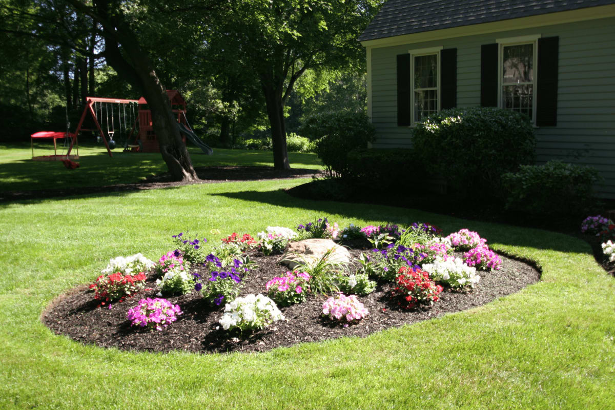 Green lawn and flower bed maintained by Burns Landscaping