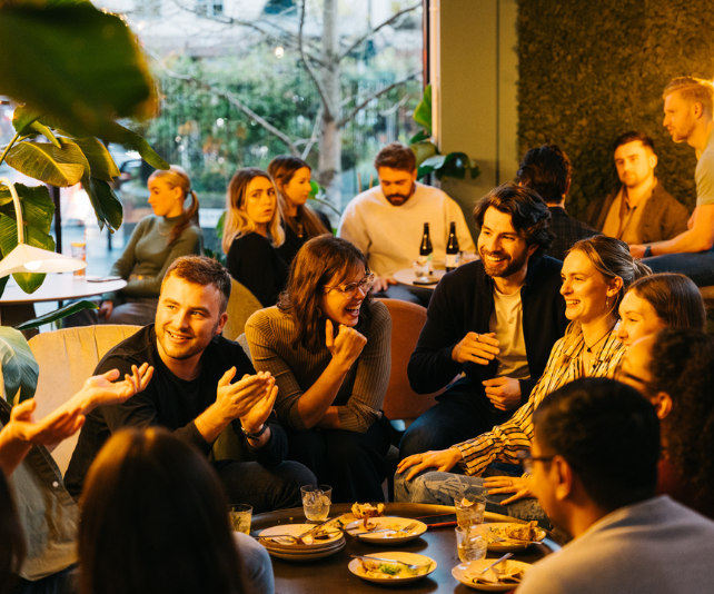A group of colleagues laughing and eating at a team party.