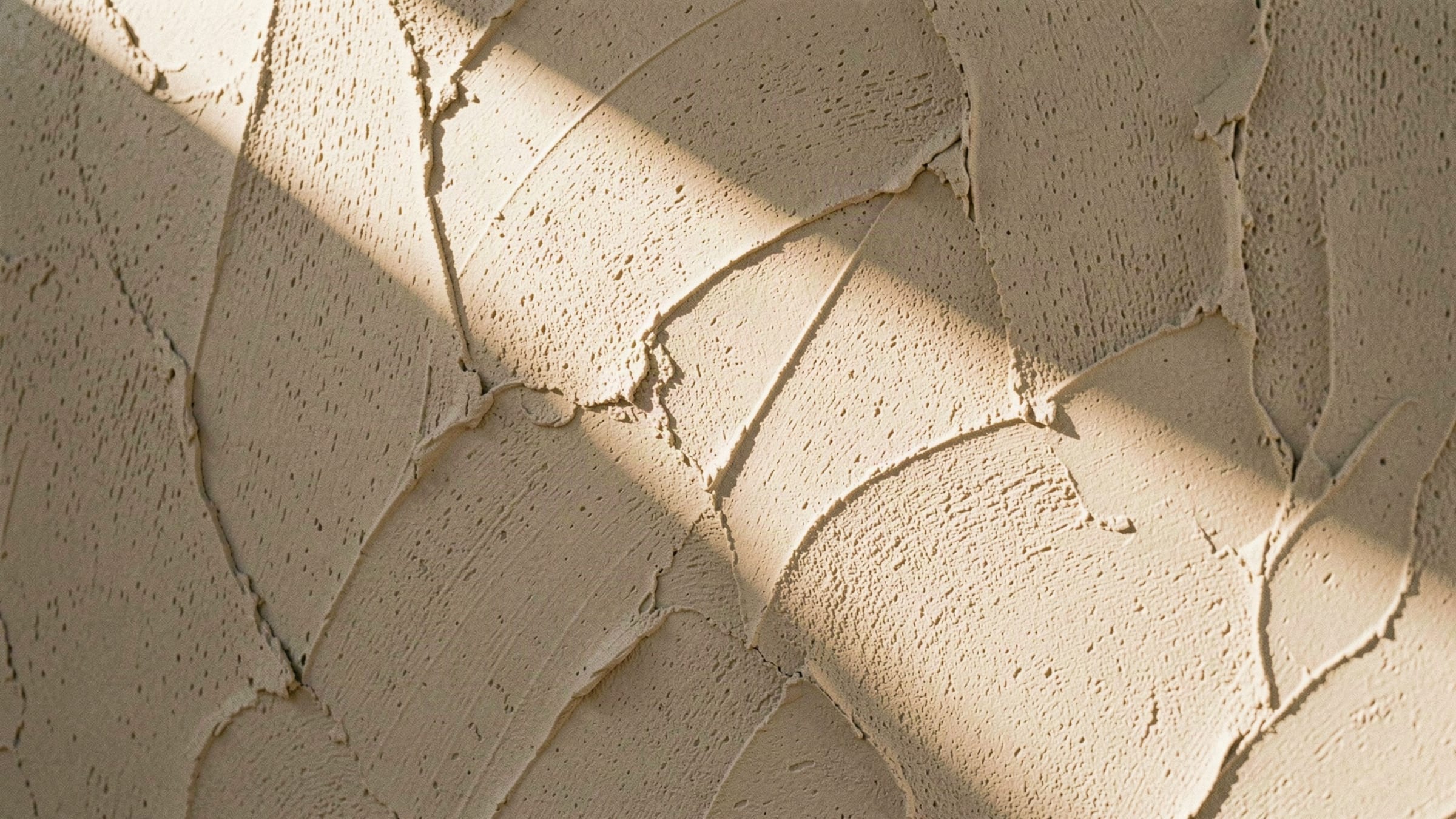 Close detail of hand-troweled limestone plaster in raking sunlight