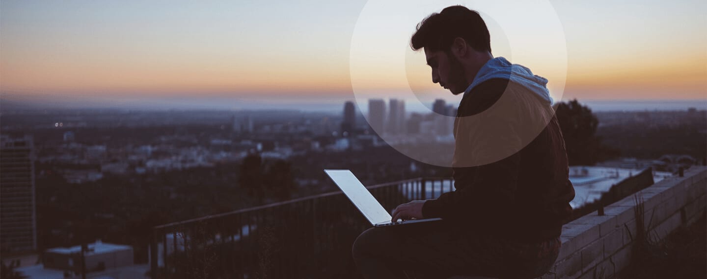 Person working on a laptop open city in the background