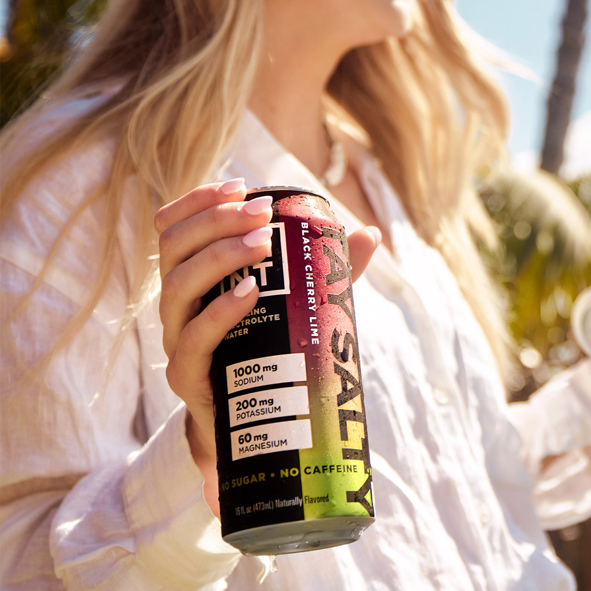 Black Cherry Lime sparkling electrolyte drink can on a gym bench with athlete nearby.