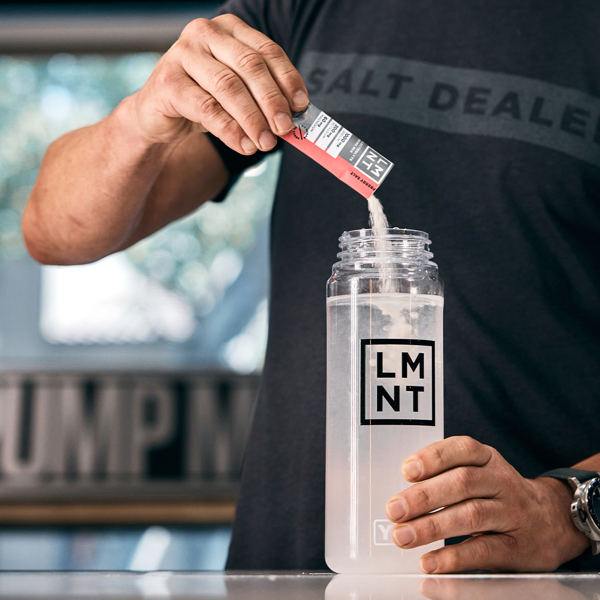 LMNT Citrus Salt drink mix and yellow 'Stay Salty' bottle on gym bench.