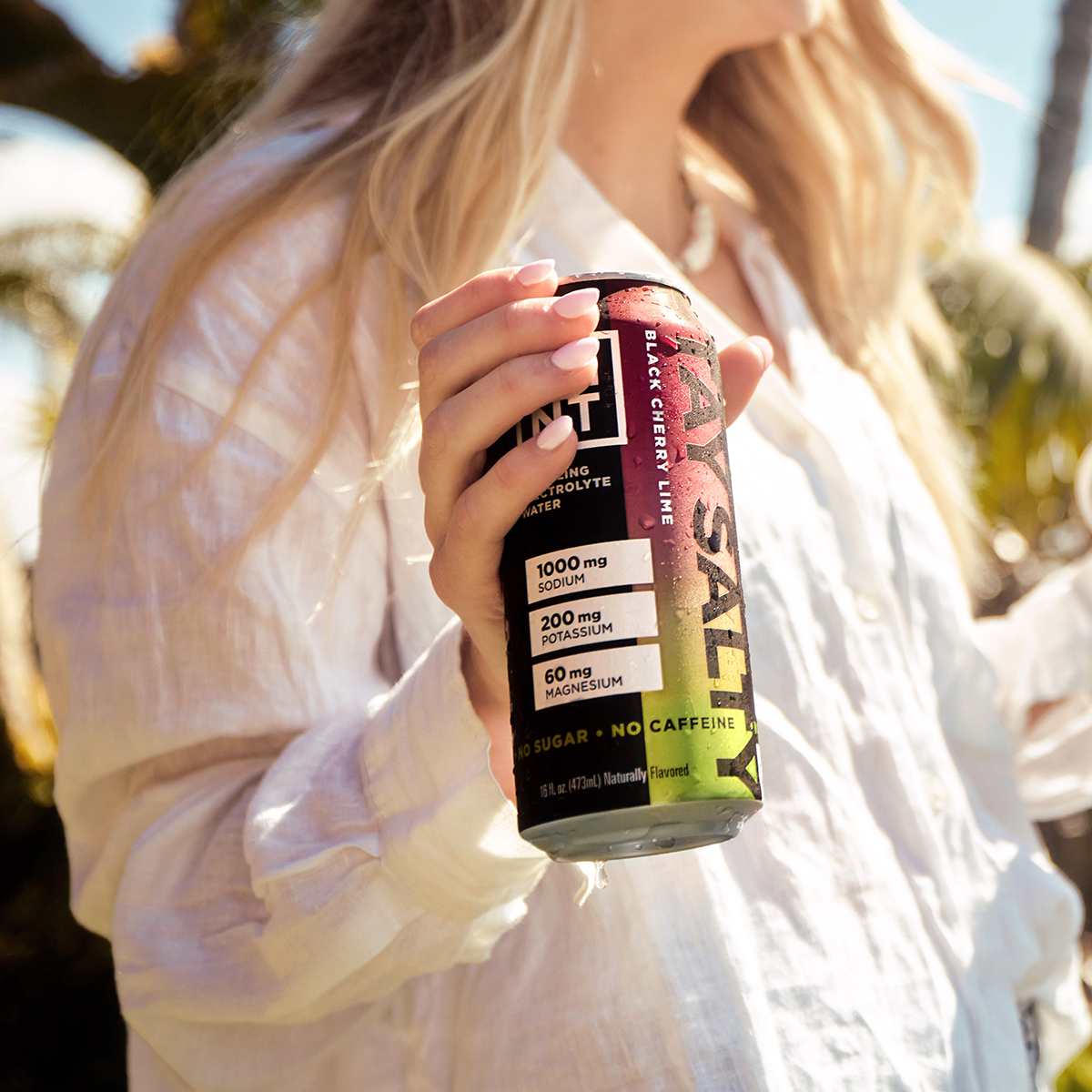 Black Cherry Lime sparkling electrolyte drink can on a gym bench with athlete nearby.