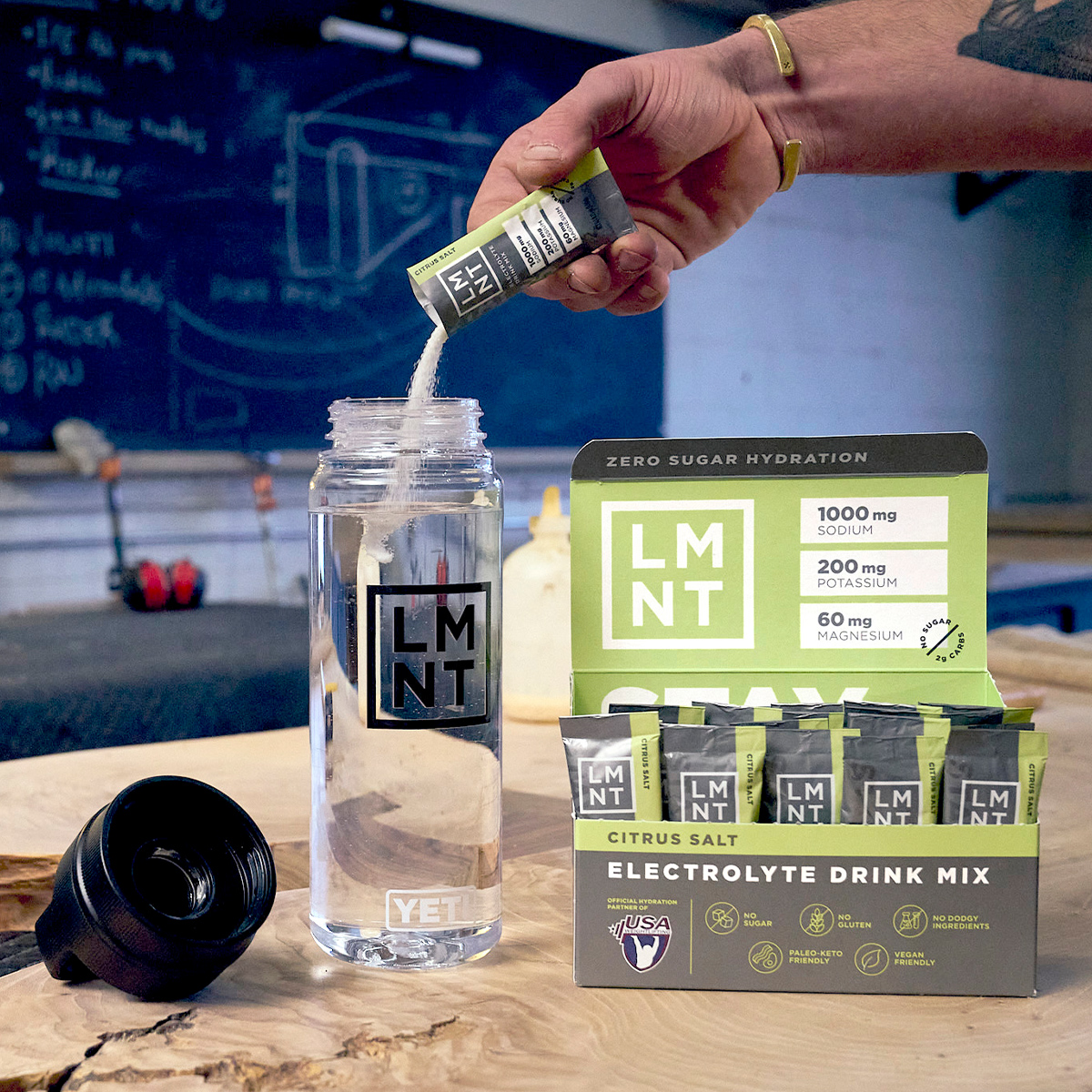 LMNT Citrus Salt drink mix and yellow 'Stay Salty' bottle on gym bench.