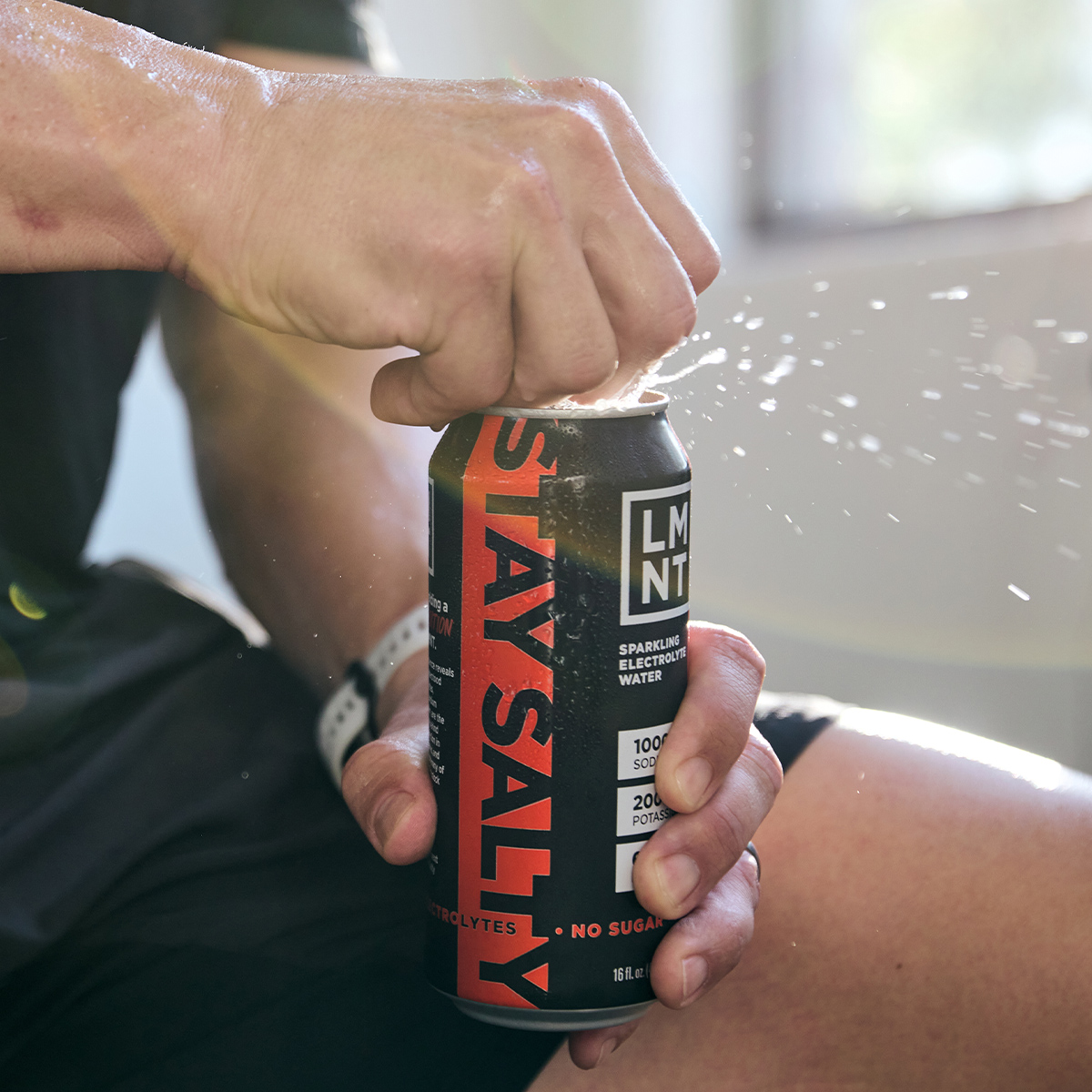 Black Cherry Lime sparkling electrolyte drink can on a gym bench with athlete nearby.