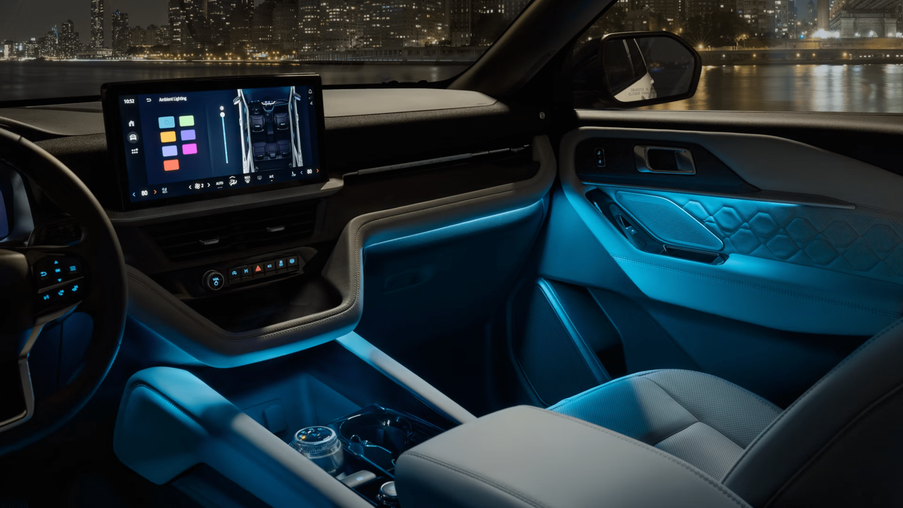 Interior of a modern car with blue ambient lighting and digital dashboard, city skyline visible through windows at night.