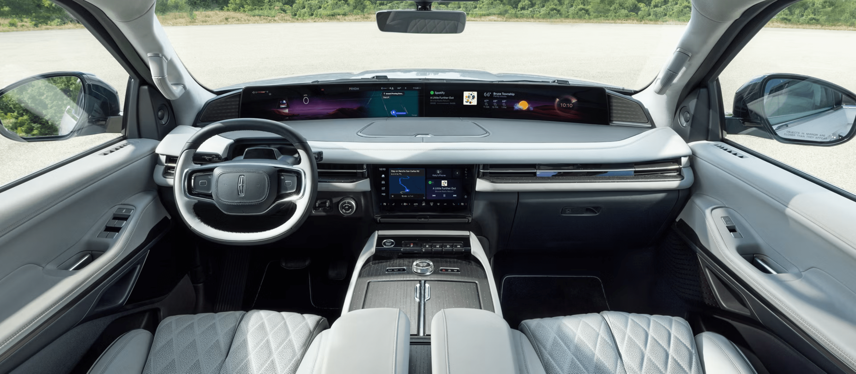 Interior of a modern car with white leather seats and a wide digital dashboard, shown against a bright outdoor background