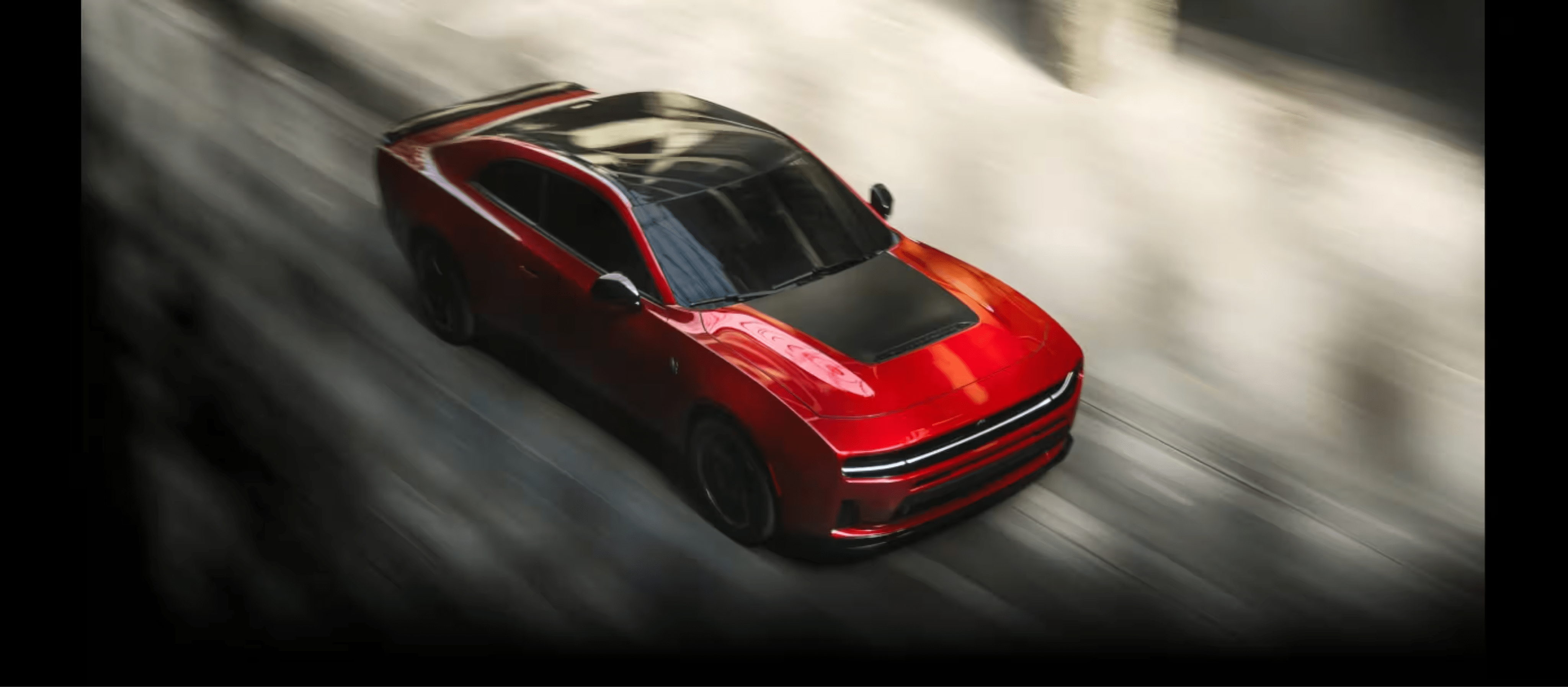 A red sports car with a black hood speeding down a blurred grey asphalt road.