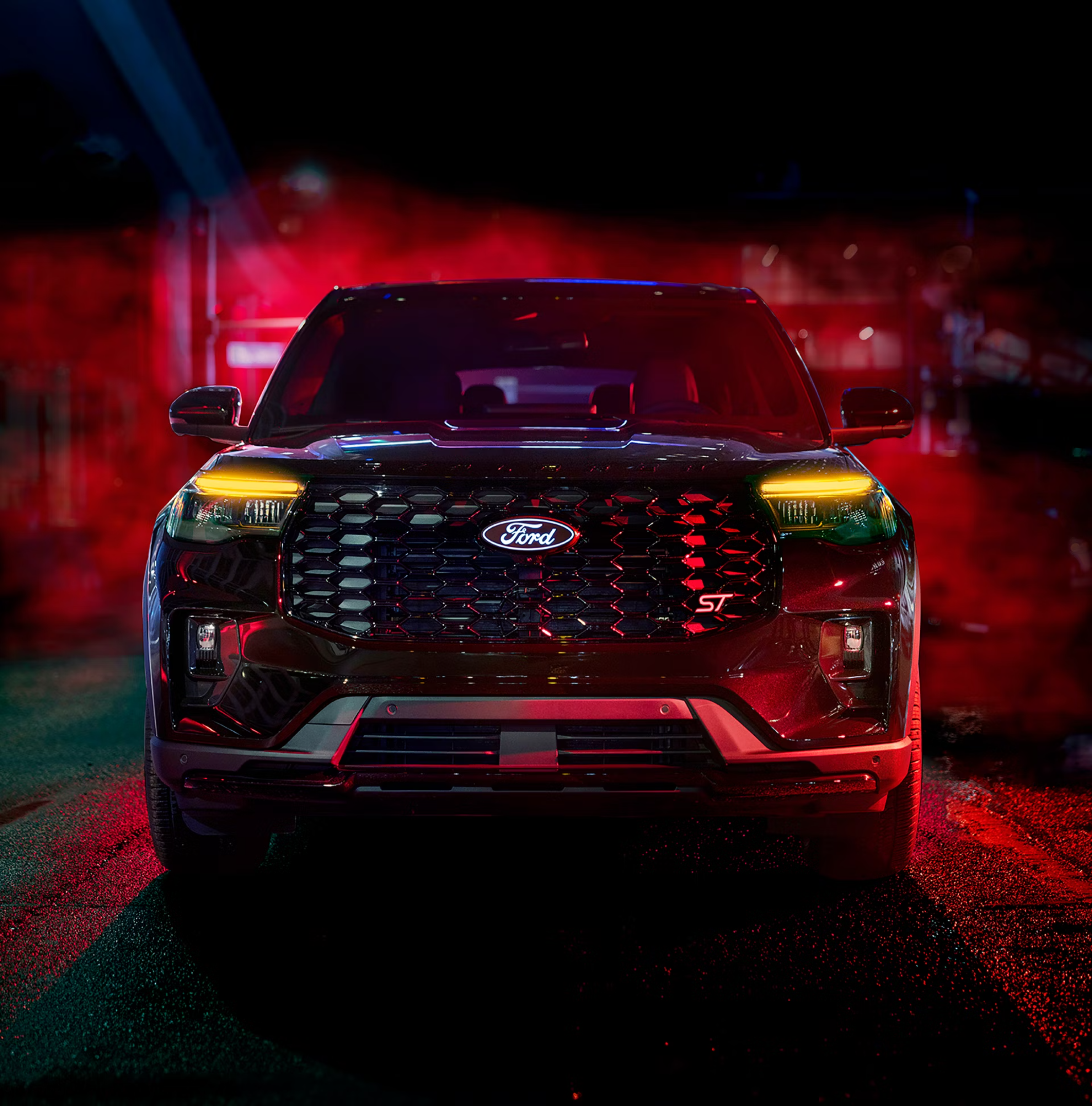 A black SUV sits in the foreground against a dark, moody background illuminated by red and blue lights.