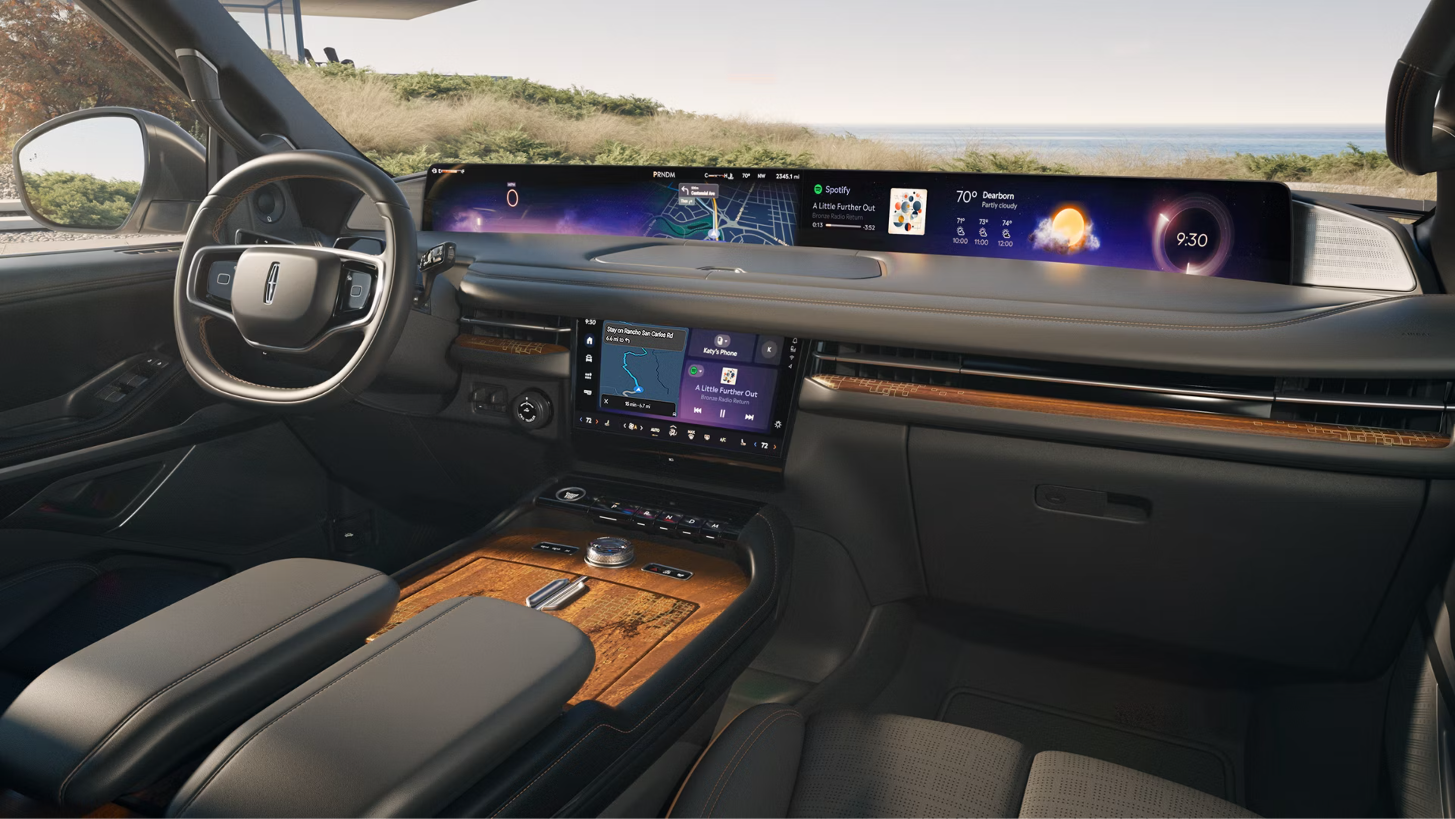 Interior of a modern vehicle showing a wide digital dashboard, steering wheel, and leather seats with a scenic coastal view through the windows.
