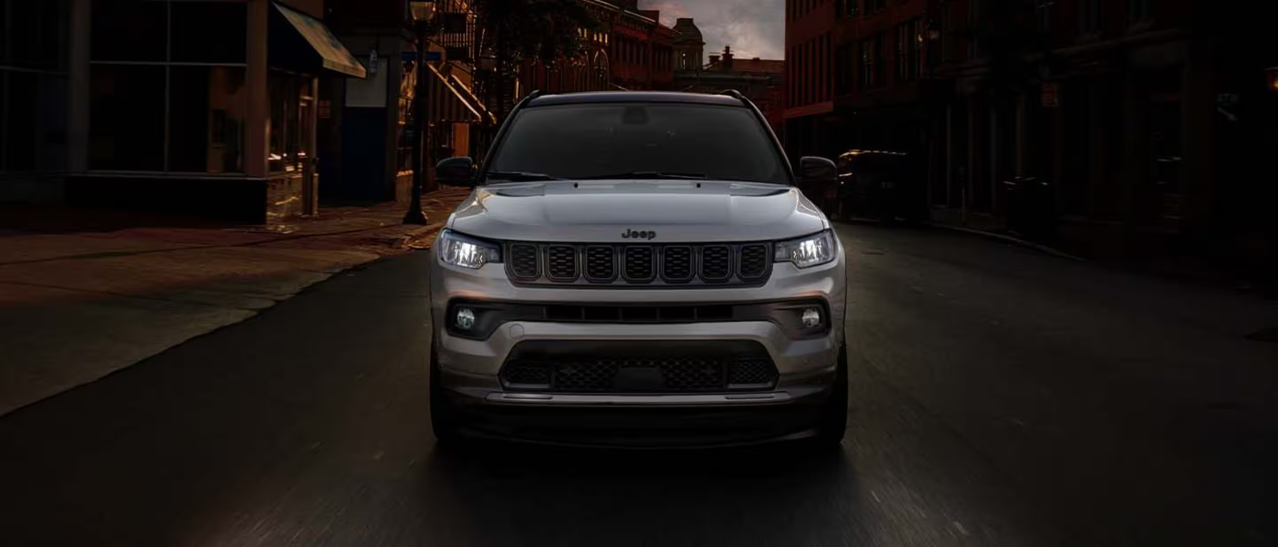 A silver SUV parked on a city street surrounded by buildings.