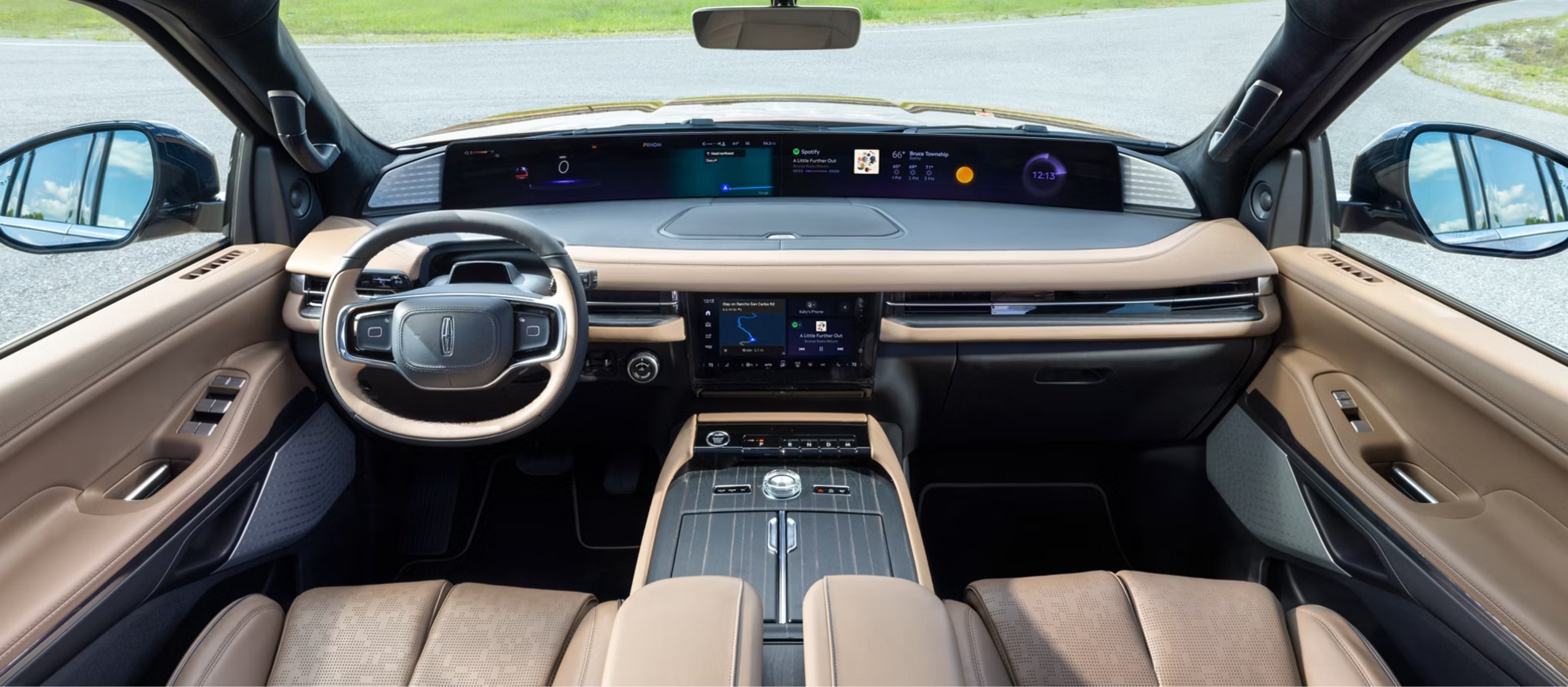 A modern luxury car interior with tan leather seats and digital displays, viewed from the rear seats with an outdoor scene visible through the windows.