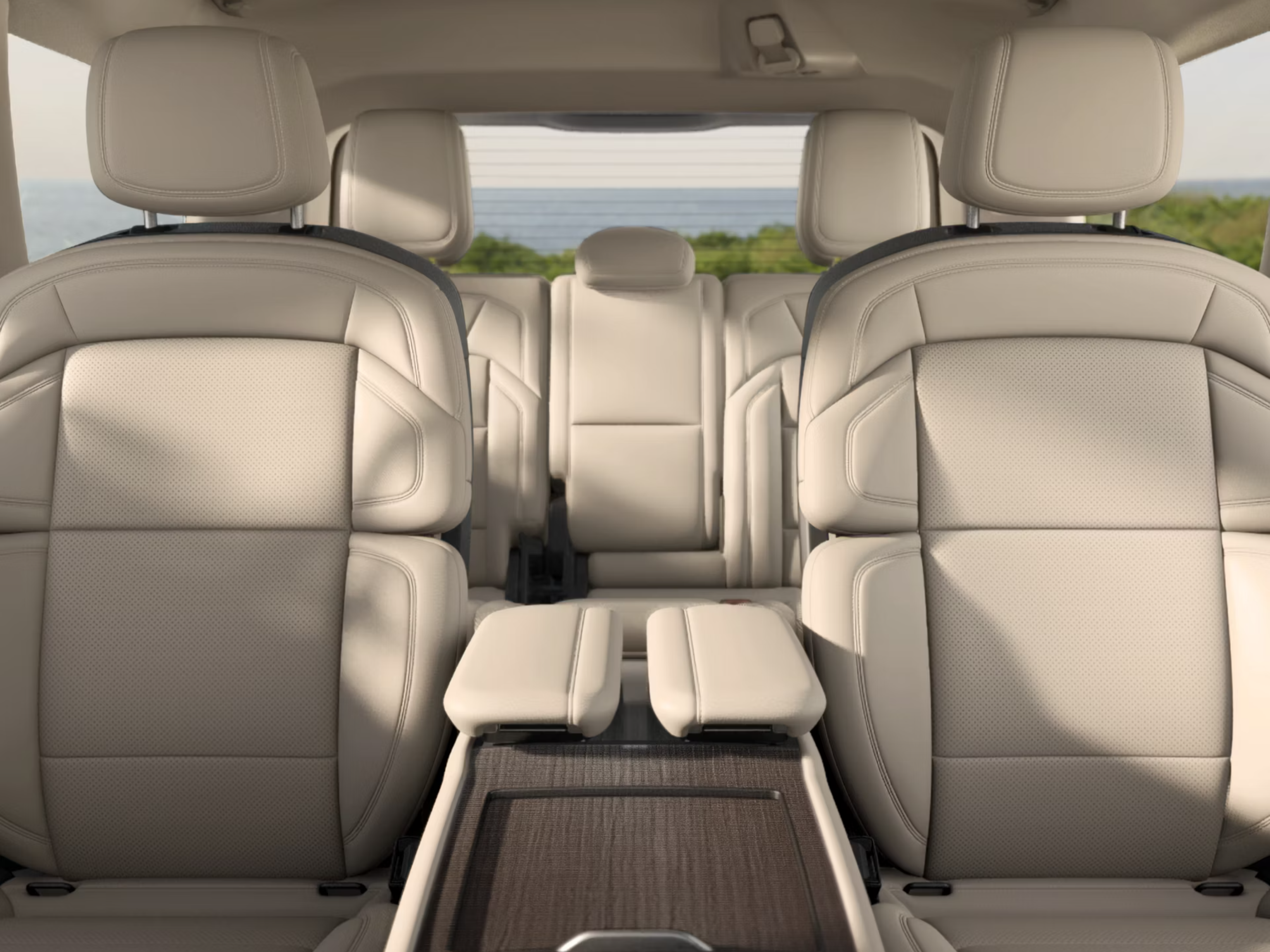 Cream leather car seats with a view of the ocean and greenery through the rear window.
