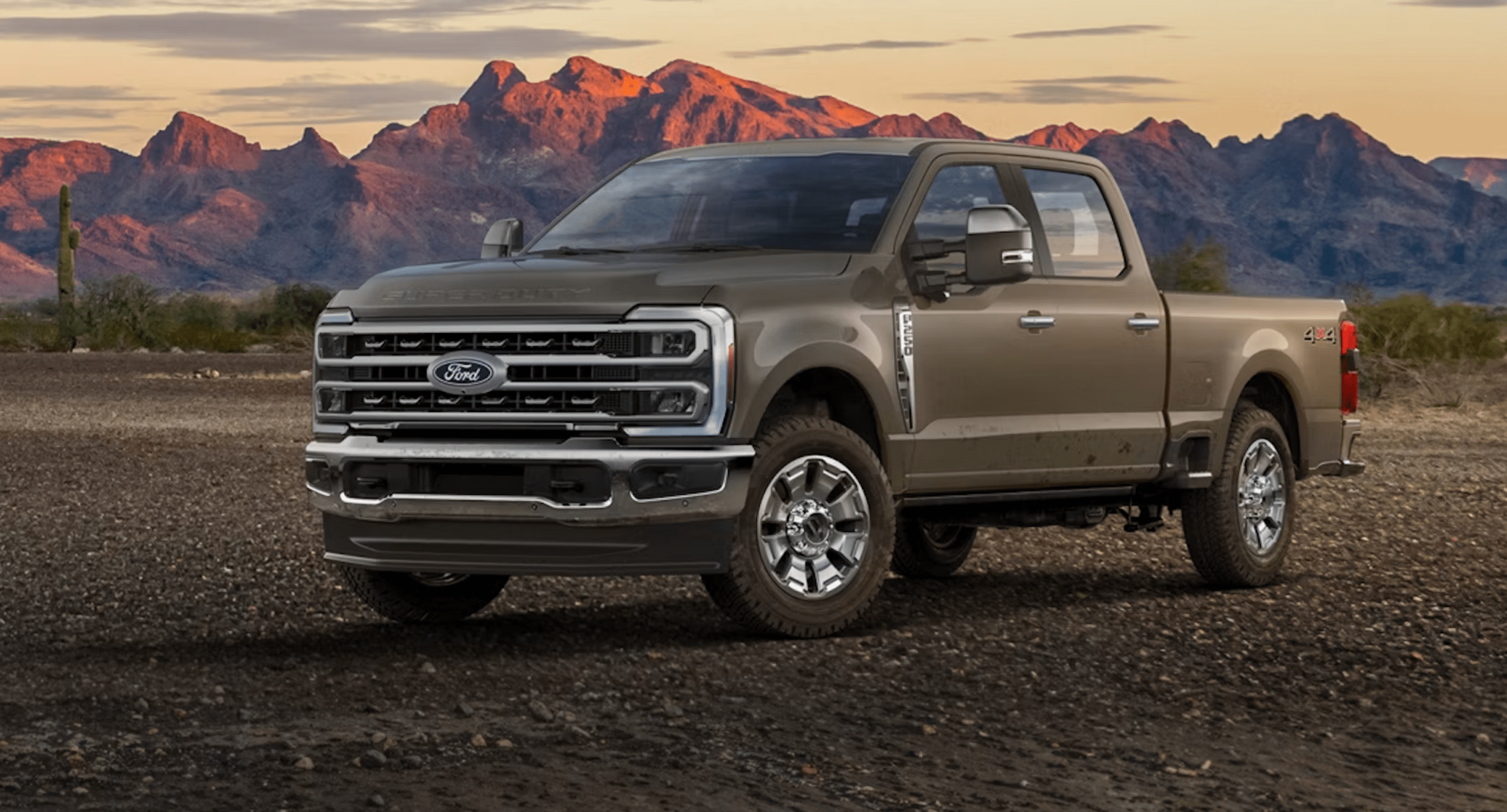A tan pickup truck on a desert plain with mountains in the background.