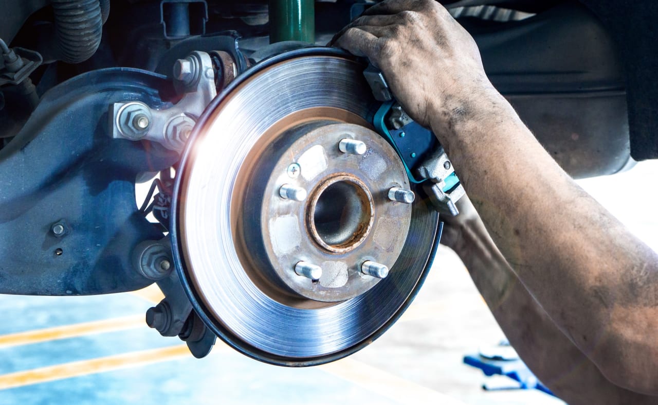 Technician servicing a Honda brake rotor and caliper at Apple Honda in Ellicott City, MD