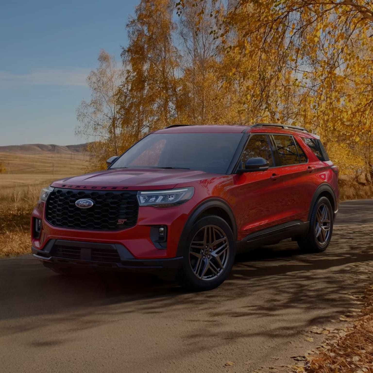 Red SUV parked on a dirt road with autumn trees in the background