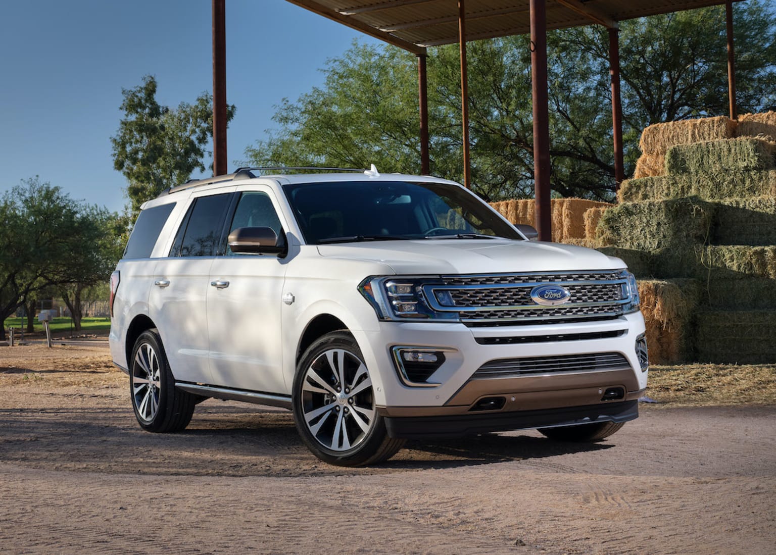 a white ford expedition vehicle parked in front of a hay bale in a parking lot with hay bales in the background