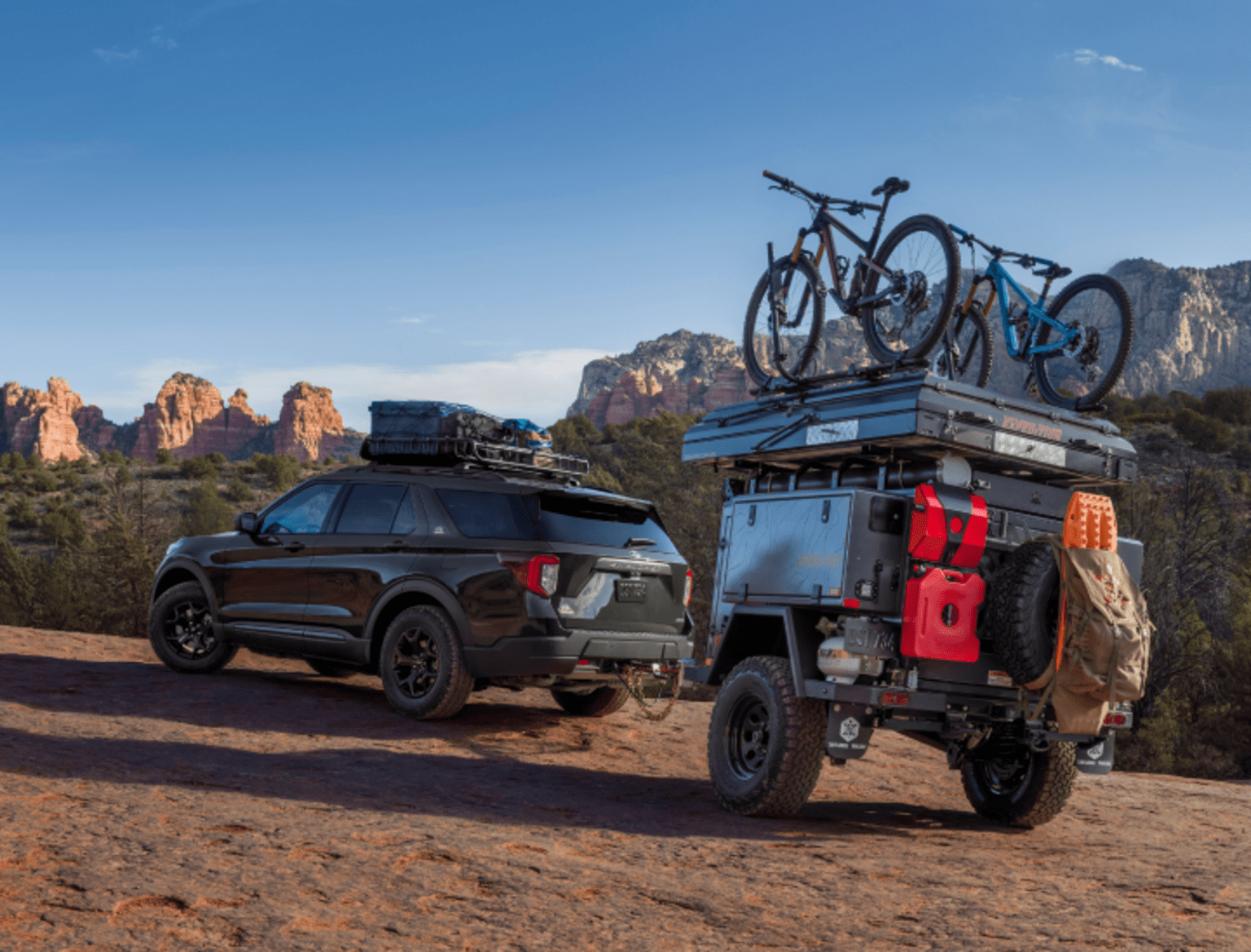 a jeep with a bike on top of it parked next to a truck with a bike on top of it