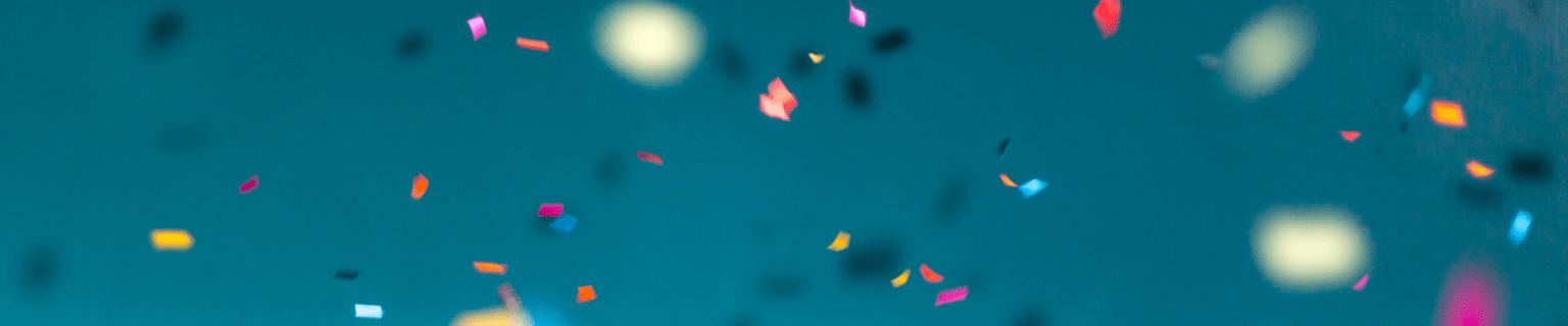 a blurry photo of confetti and streamers in the air with a blue sky in the background