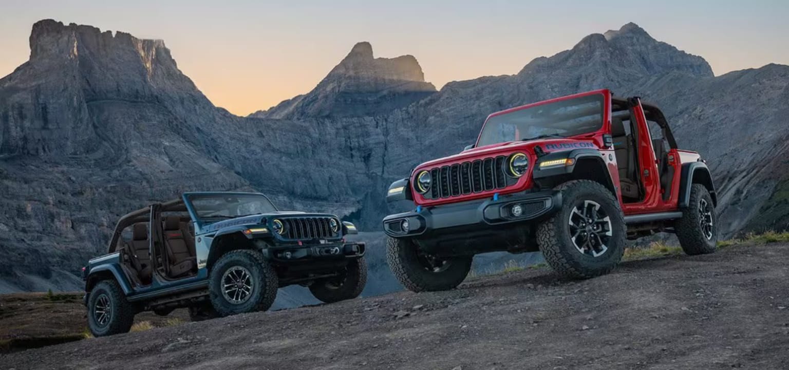 Off-road vehicles parked in a mountainous landscape with rock formations in the background.