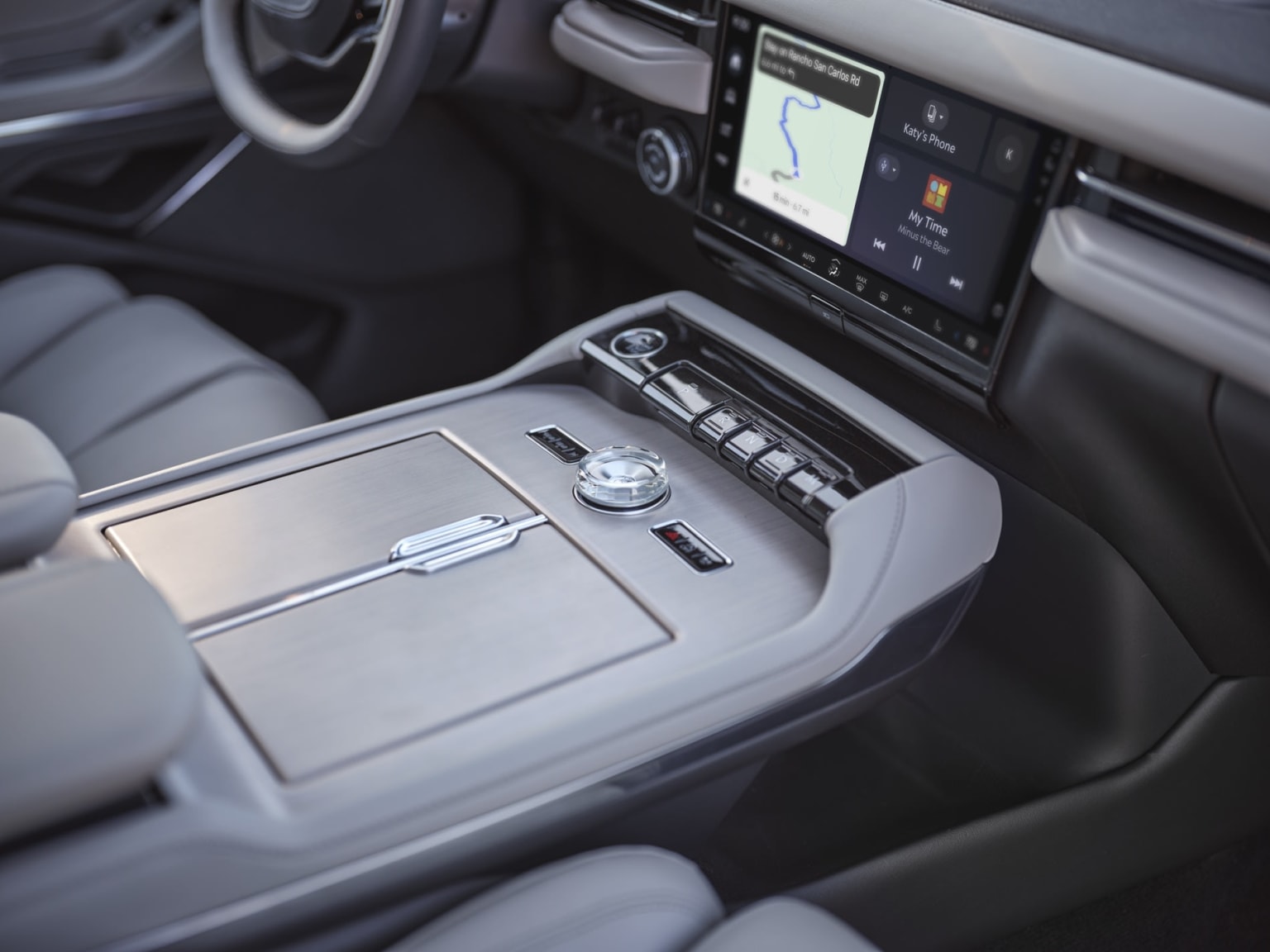 Interior of a modern vehicle with a large touchscreen display in the center console, various controls and buttons, and a sleek, minimalist design.