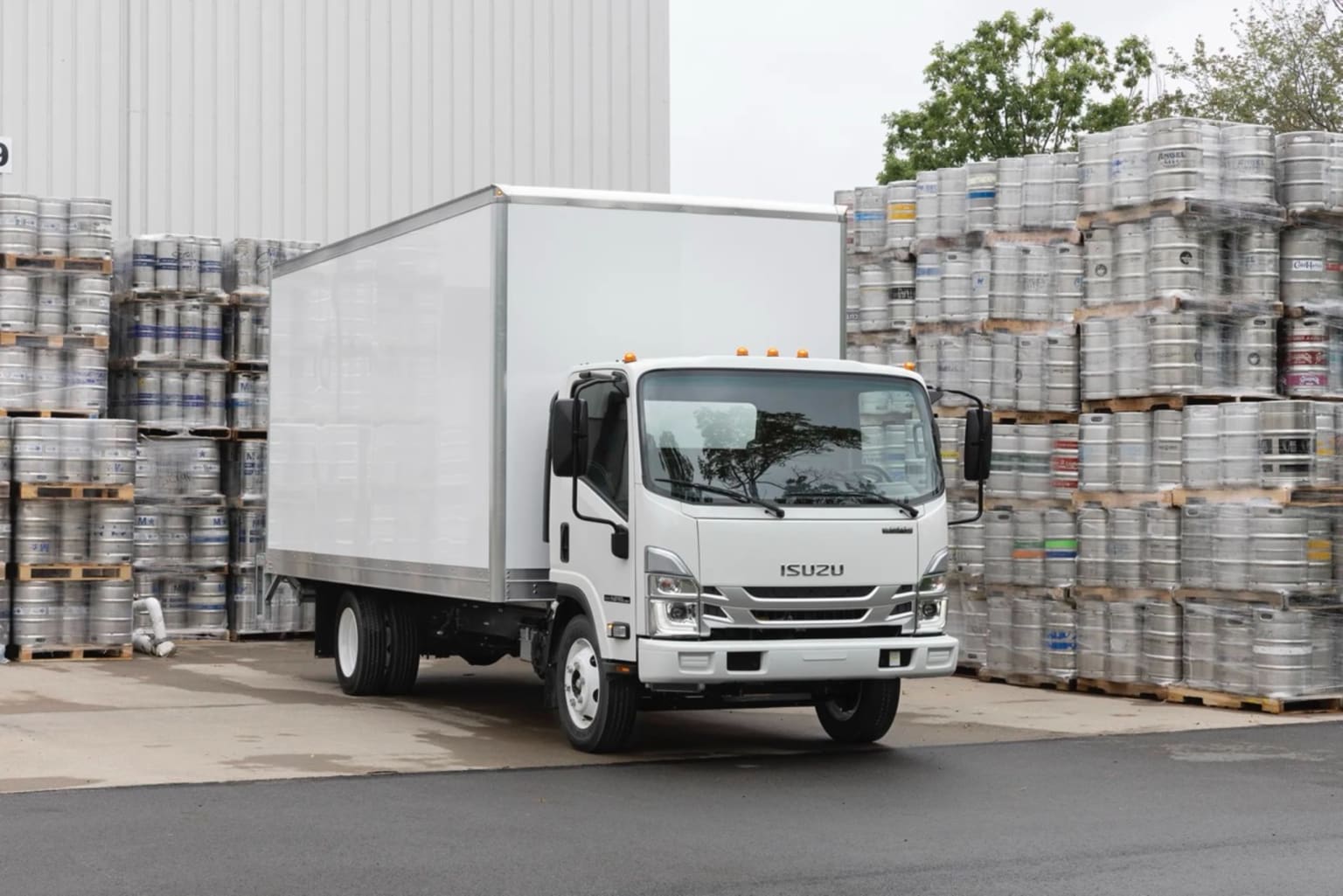A white delivery truck is parked in the foreground, surrounded by stacks of plastic containers in the background.