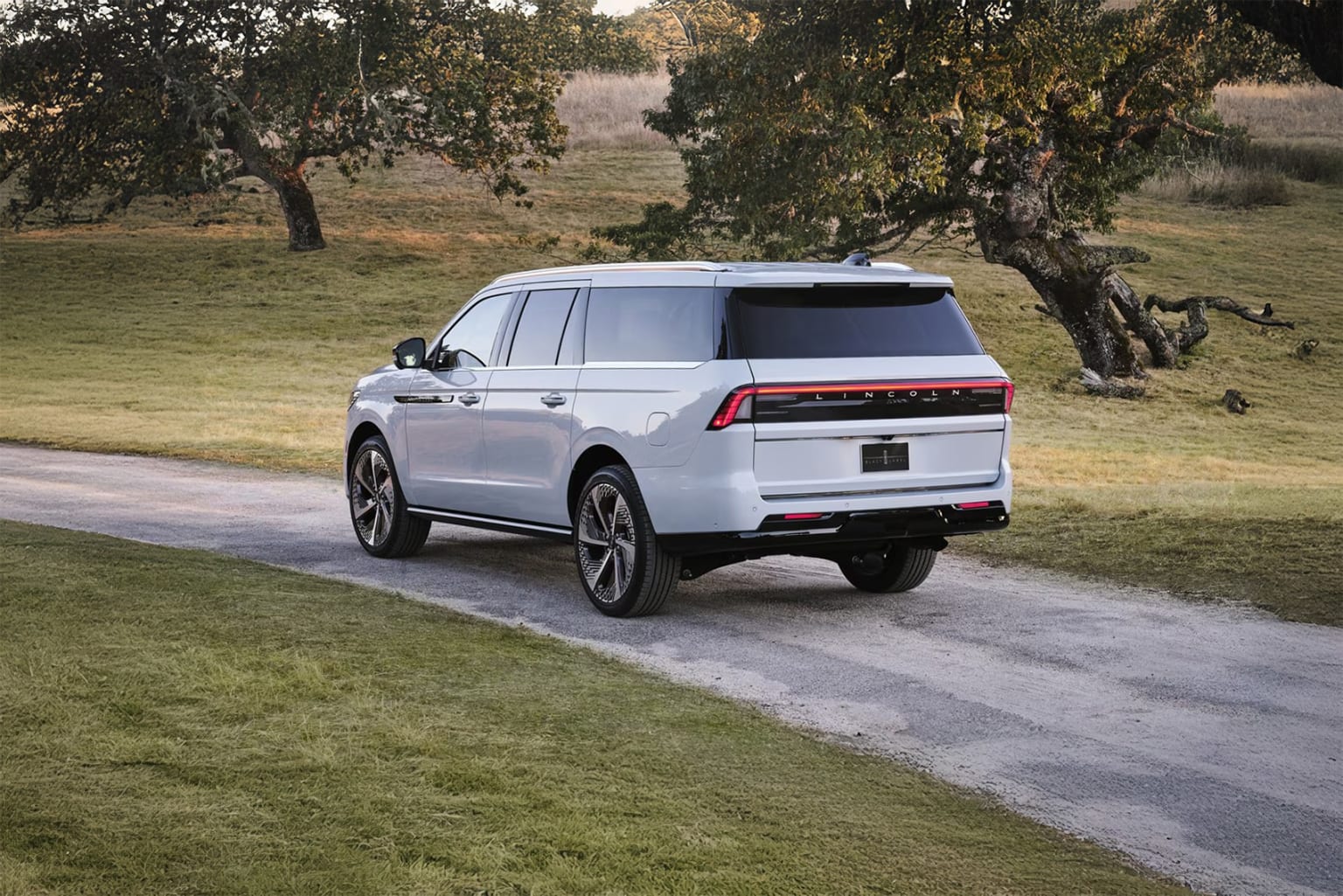 A large white SUV parked in a scenic outdoor setting surrounded by lush trees and vegetation.
