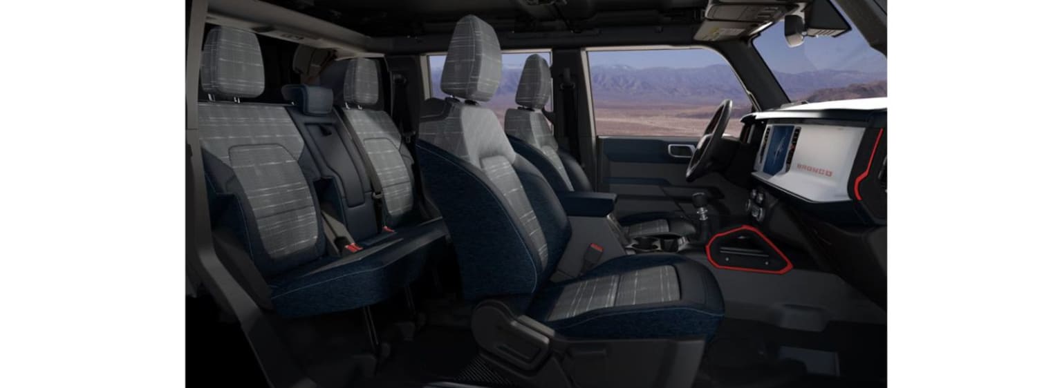 The image shows the interior of a vehicle, with multiple rows of seats and a view of the desert landscape through the windshield.