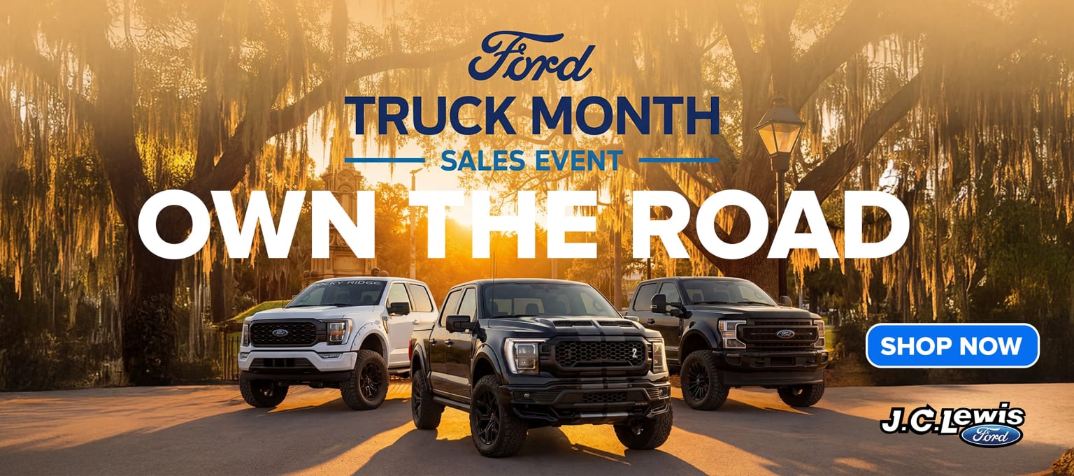 Three trucks on display at a dealership with a nature-themed backdrop setting for a sales event.