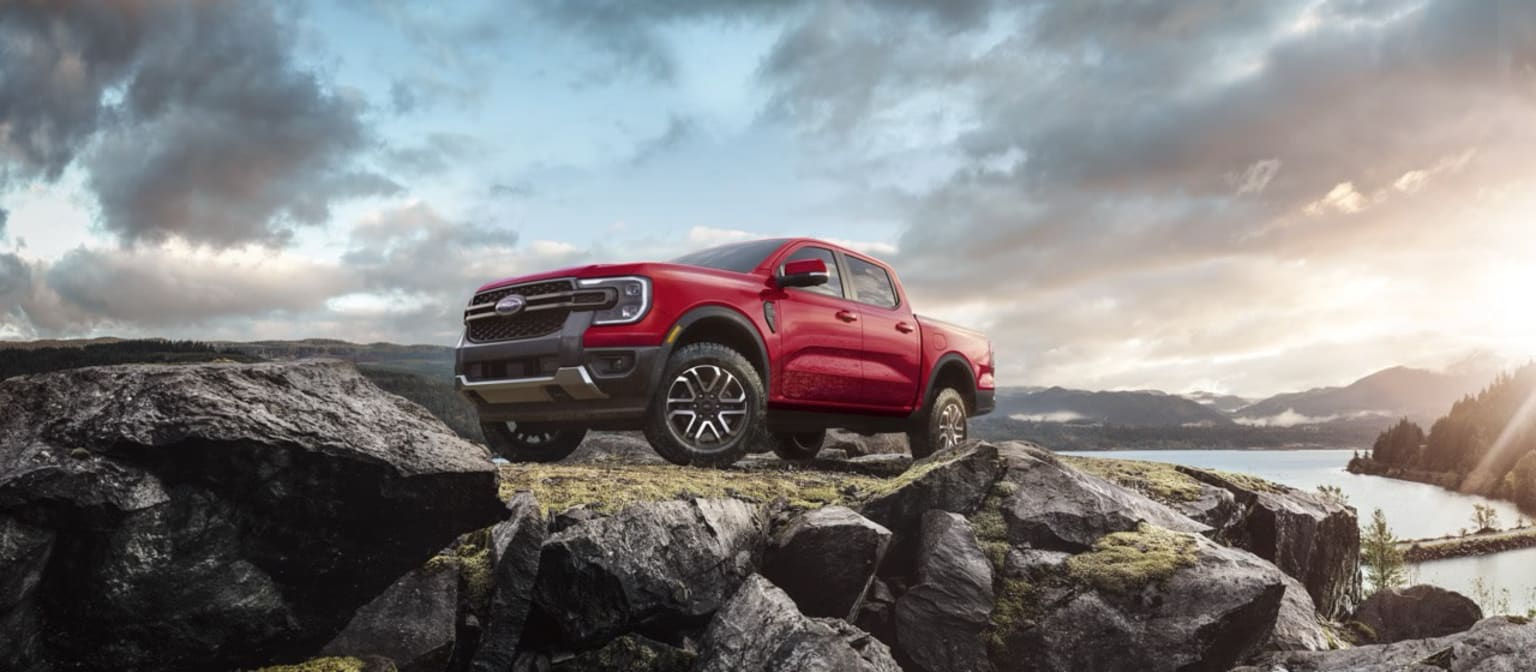 Off-road vehicle on rocky terrain with dramatic sky and mountains in the background.