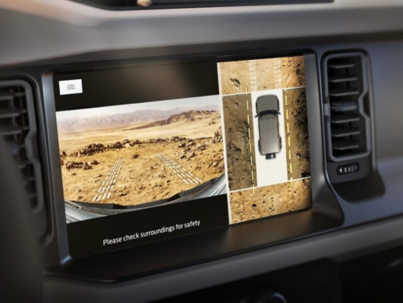 The image shows a vehicle's dashboard display, featuring a bird's-eye view of a desert landscape with a road winding through it.