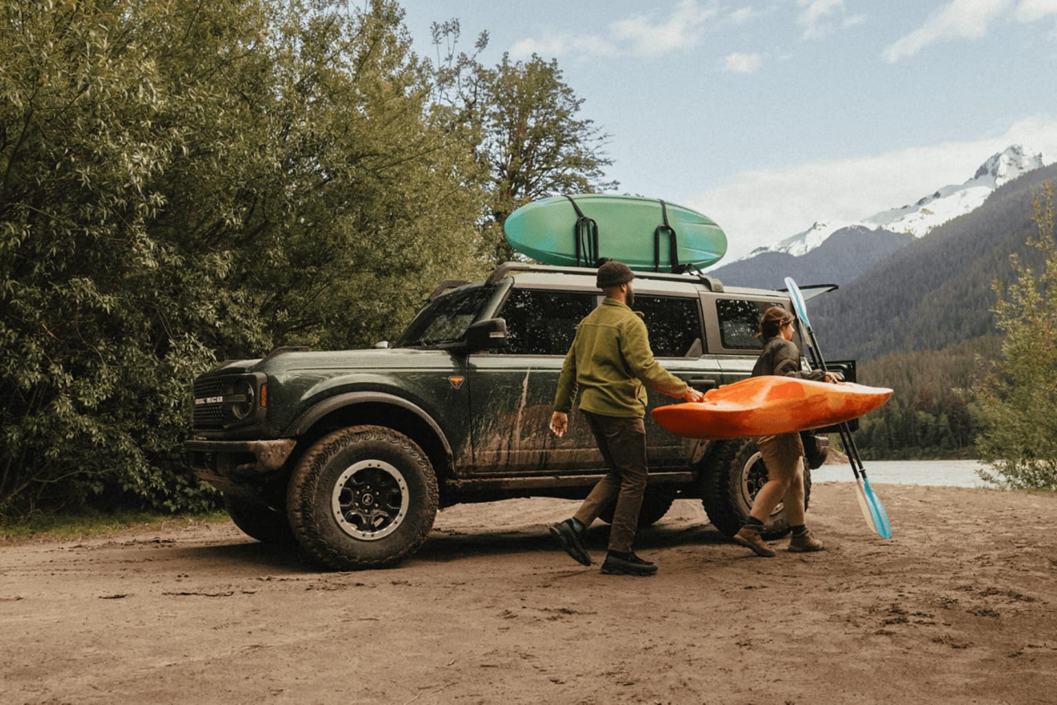 Off-road vehicle with a kayak on roof in nature landscape.